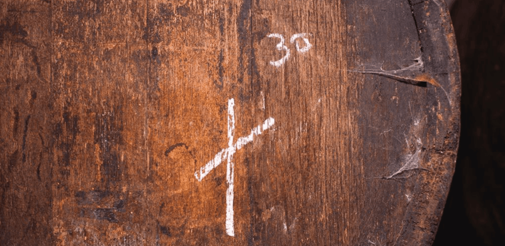 Gros plan sur le fond usé d'un vieux fût en bois marqué d'une croix blanche et du chiffre "30" à la craie, évoquant la sélection minutieuse des soleras pour le Palo Cortado par Equipo Navazos.